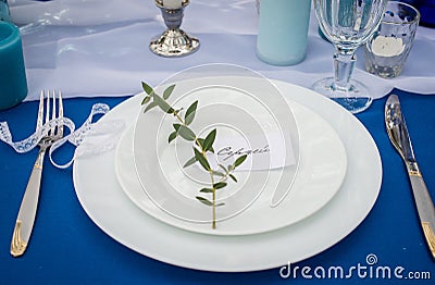 White plates on the banquet table with guestâ€™s name Sergei and a branch of eucalyptus. Stock Photo